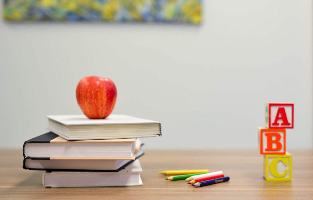 机の上に本と鉛筆とリンゴの模型